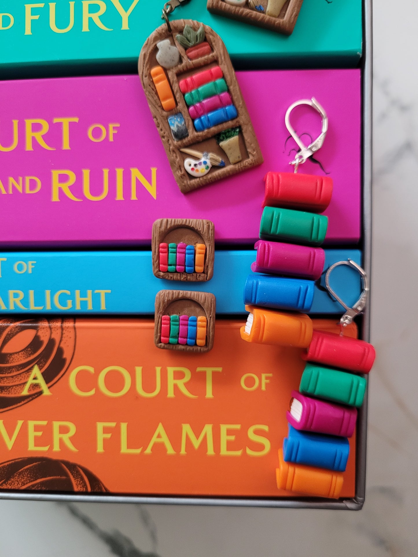 The ACOTAR bookshelf and bookstack collection lying on top of the actual ACOTAR Paperback books.