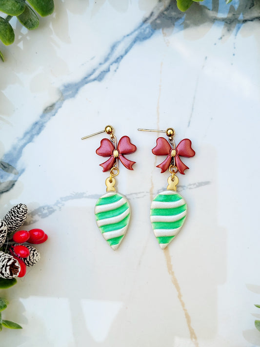 close upof ball stud retro ornament style earrings on a marble background surrounded by foliage.