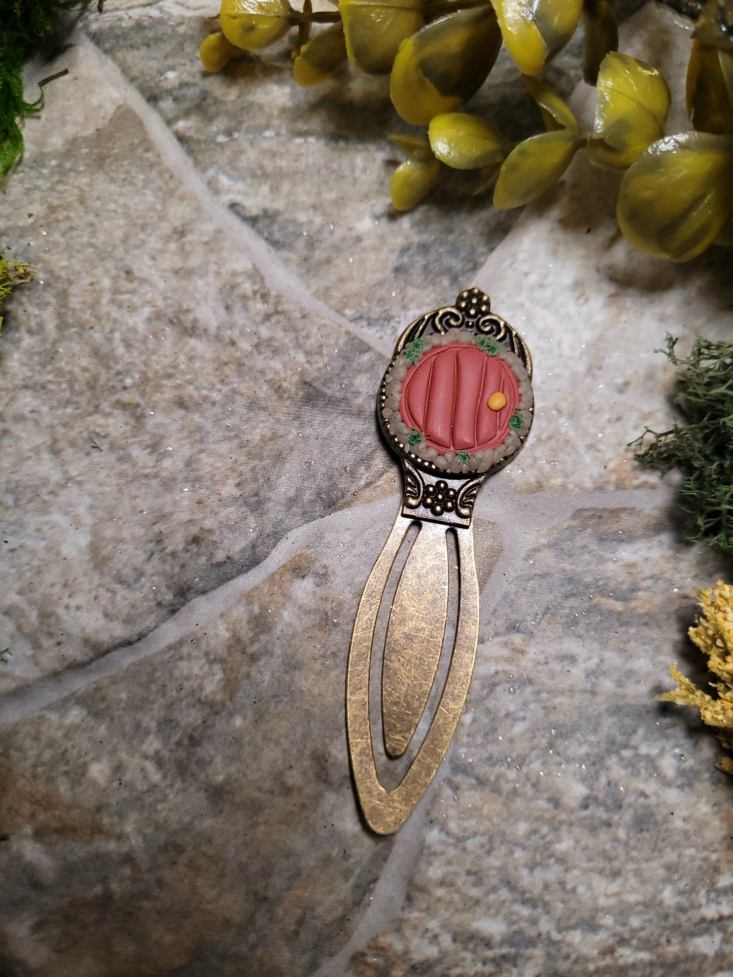 Fairy door bookmark on a stone background surrounded by foliage