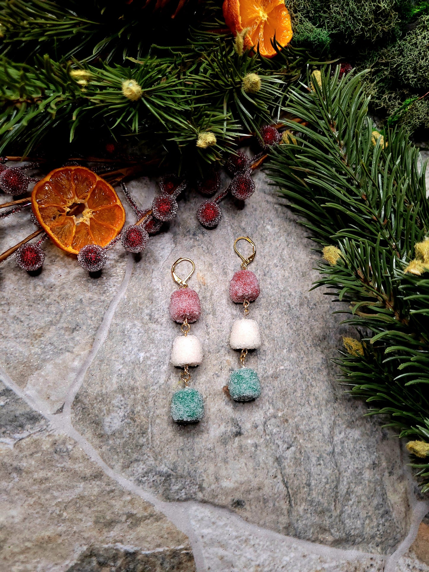 Triple Gumdrop Dangle earrings on a stone background surrounded by foliage