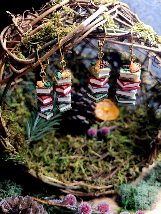 Festive Bookstack Earring on a wood and moss background surrounded by foliage.