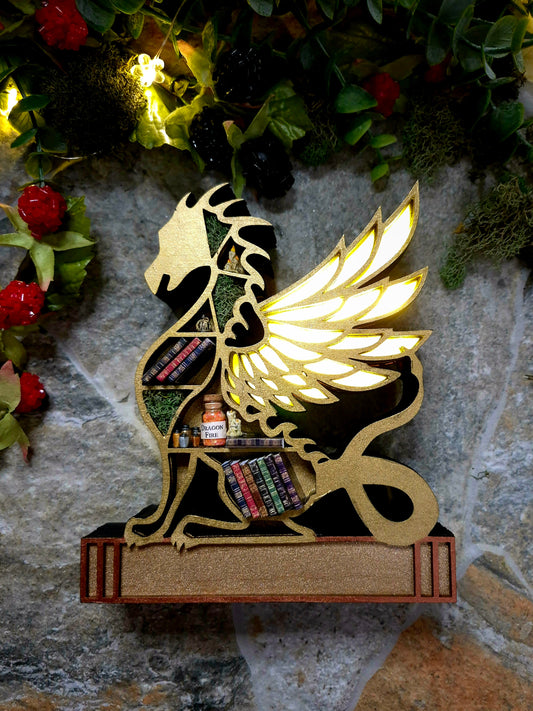 Lit up Gold dragon mini bookcase on a stone background surrounded by foliage.
