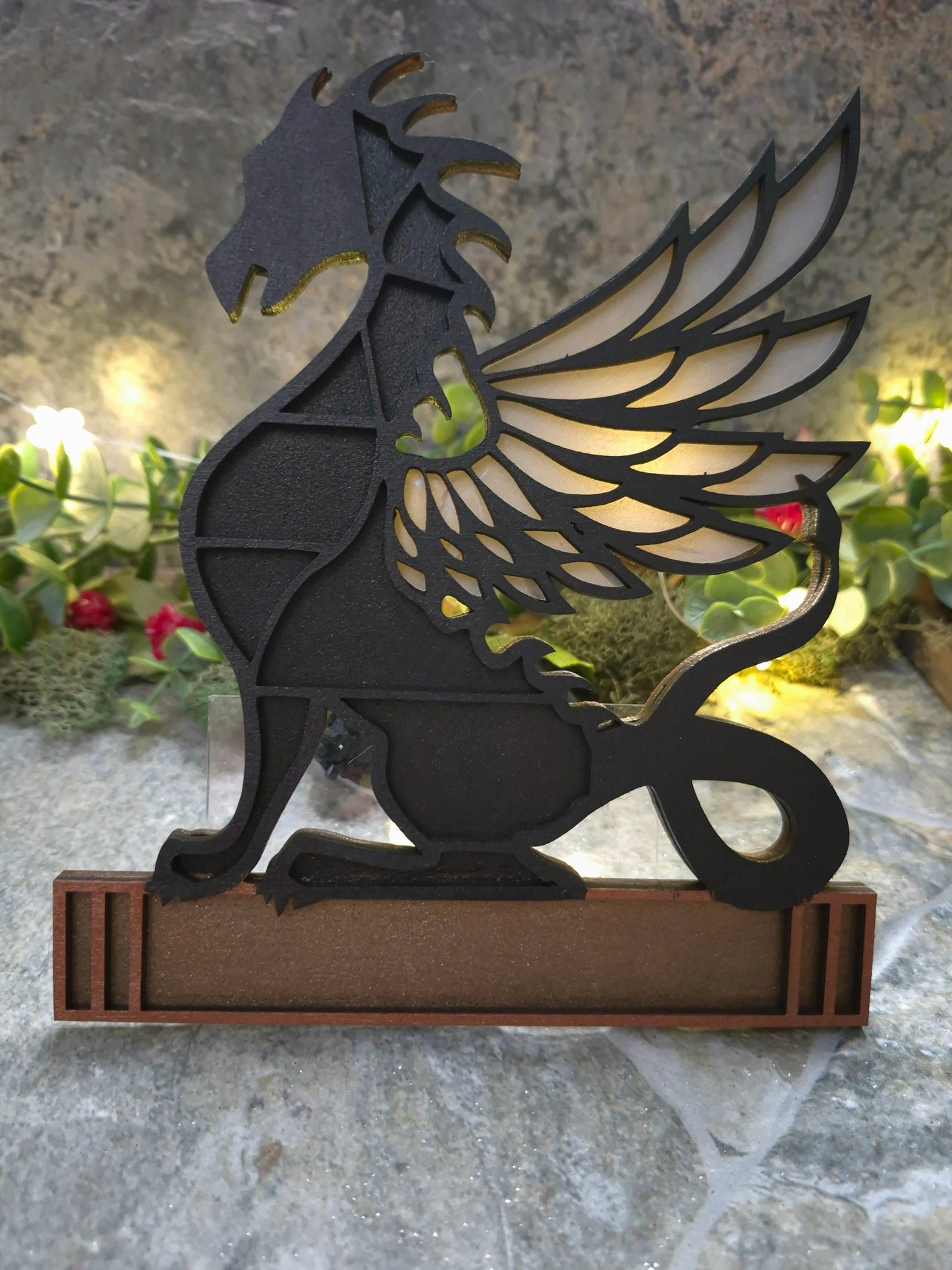 Black dragon mini bookcase on a stone background surrounded by foliage.