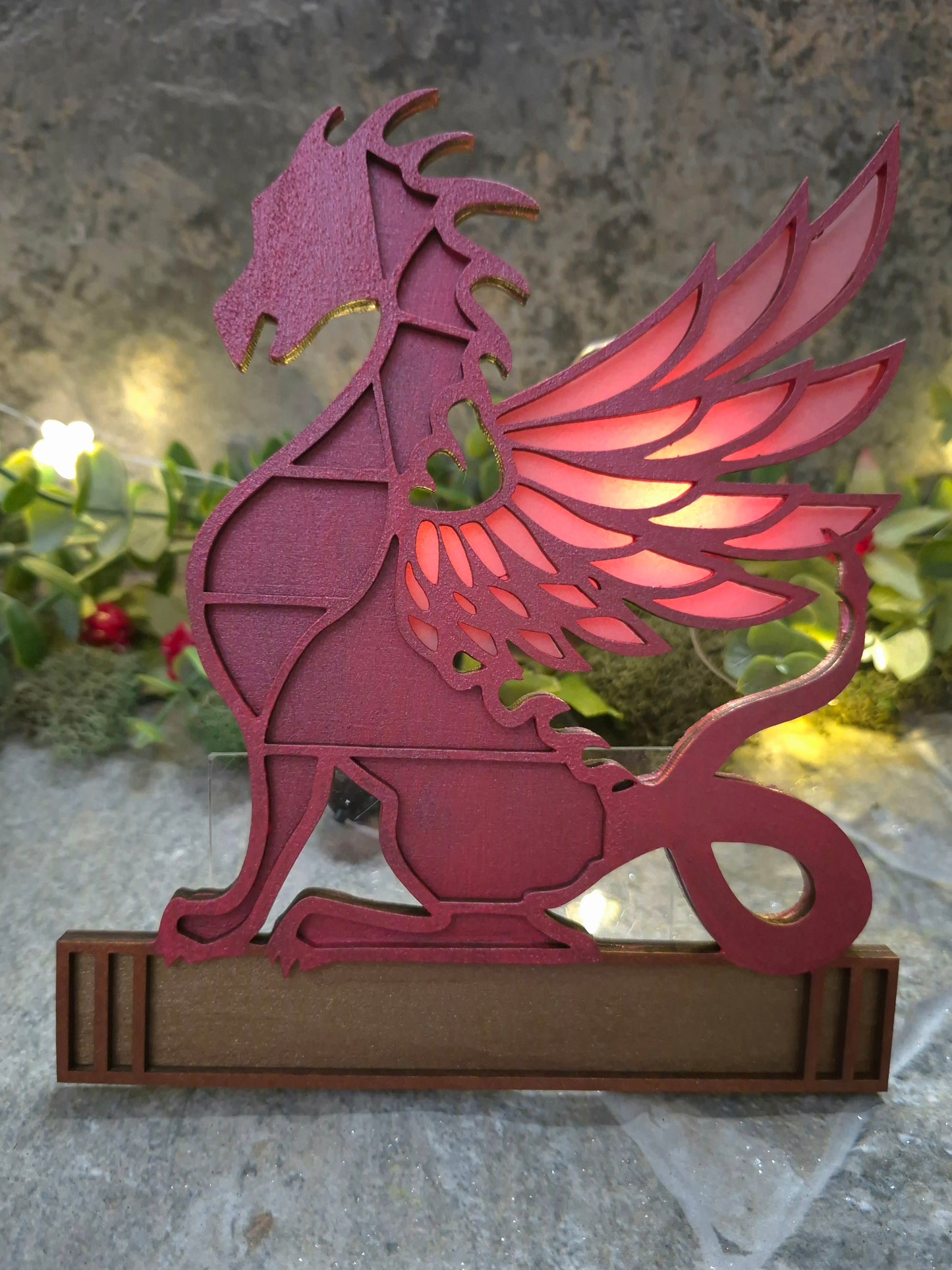 red dragon mini bookcase on a stone background surrounded by foliage.