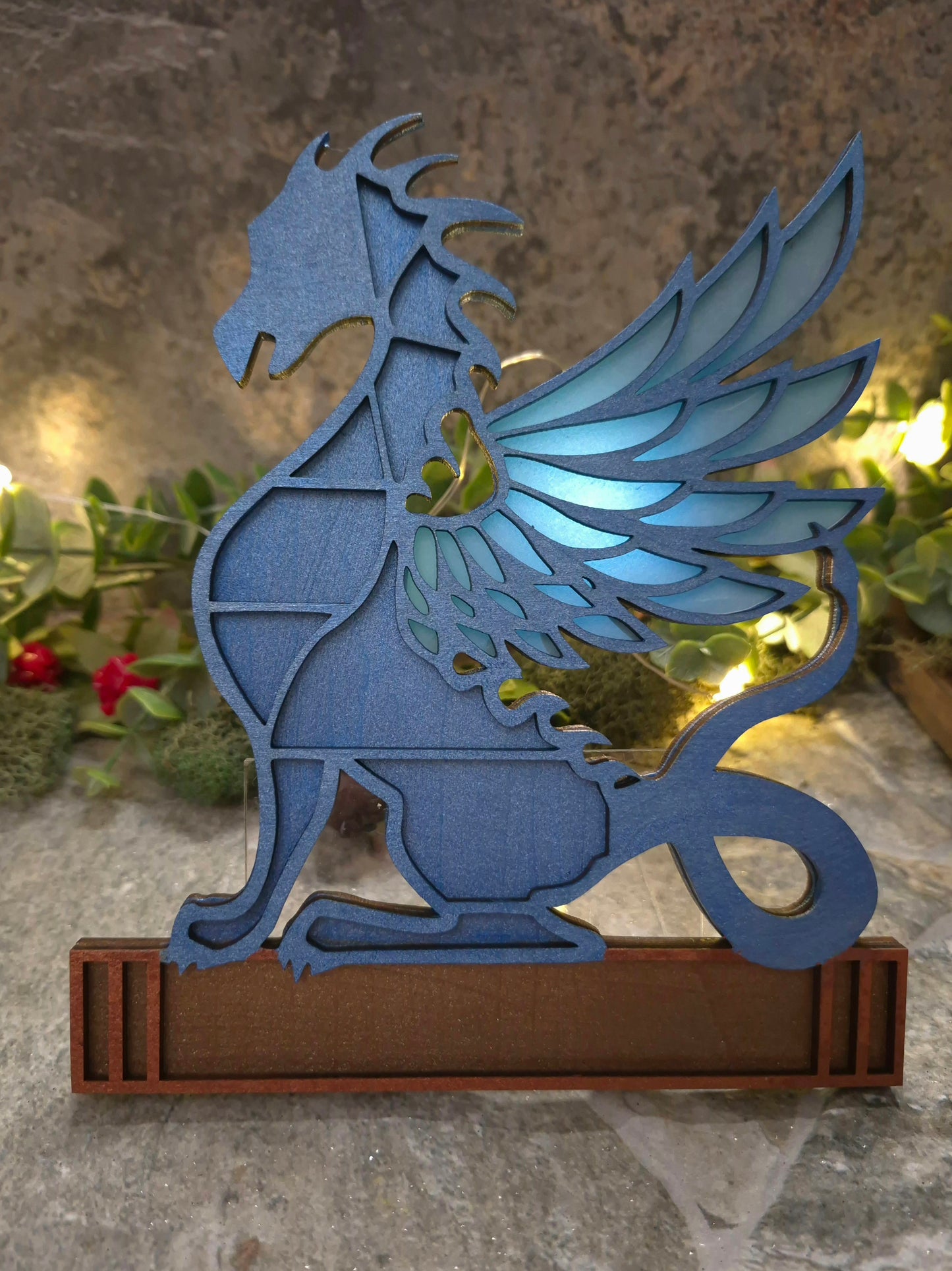 blue dragon mini bookcase on a stone background surrounded by foliage.
