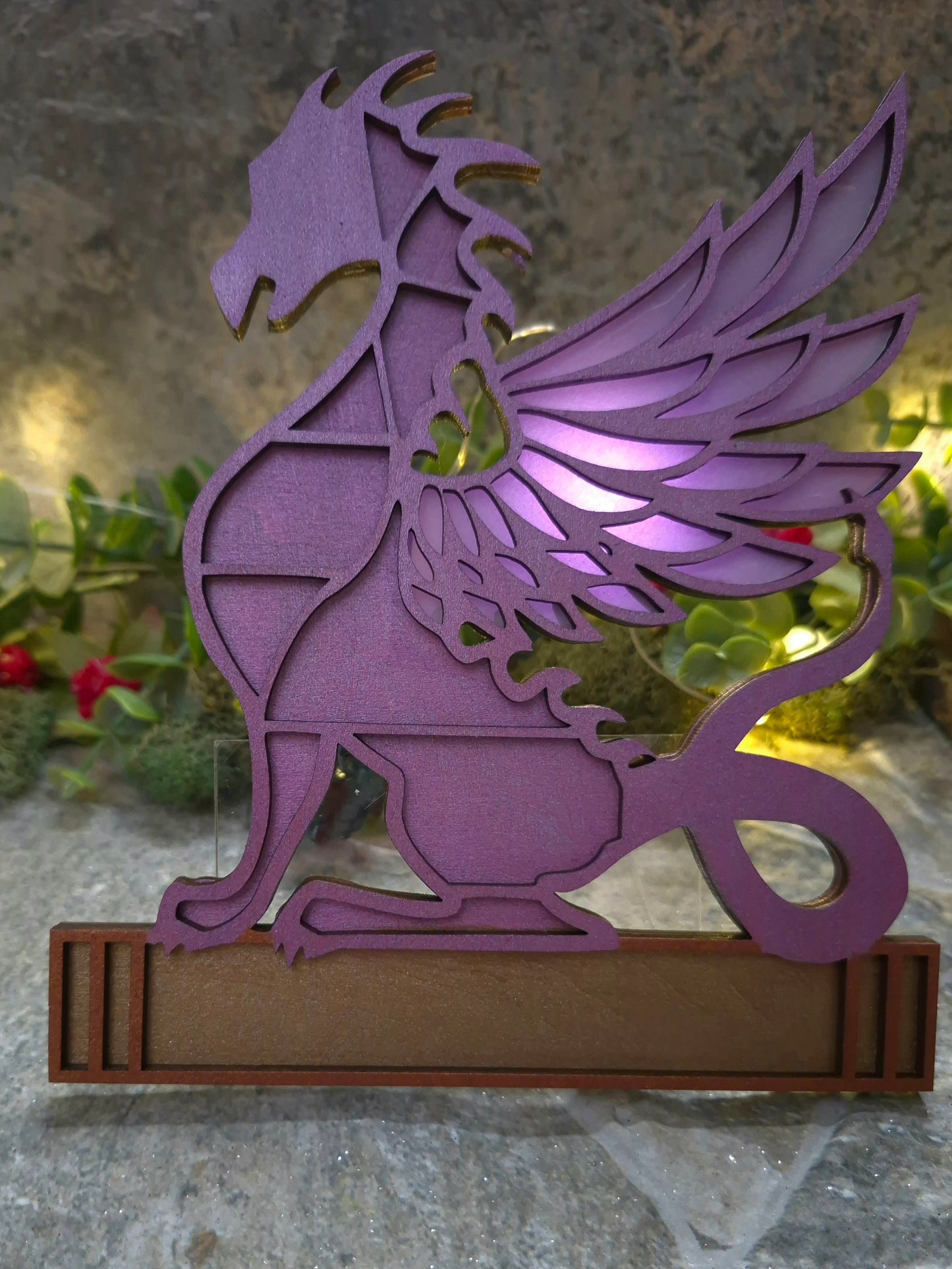 purple dragon mini bookcase on a stone background surrounded by foliage.