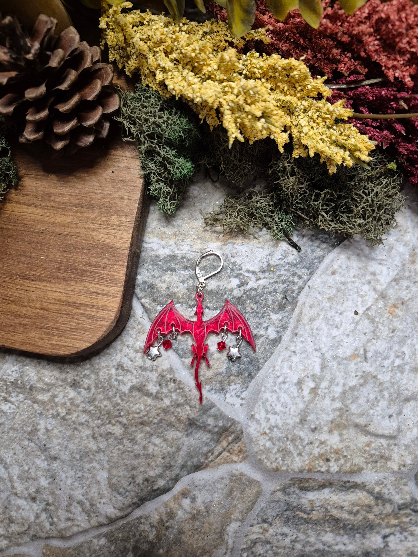 red dragon dangle on a stone background surrounded by foliage.