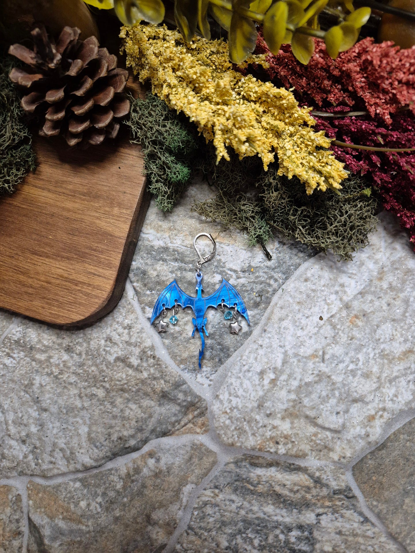 blue dragon dangle on a stone background surrounded by foliage.