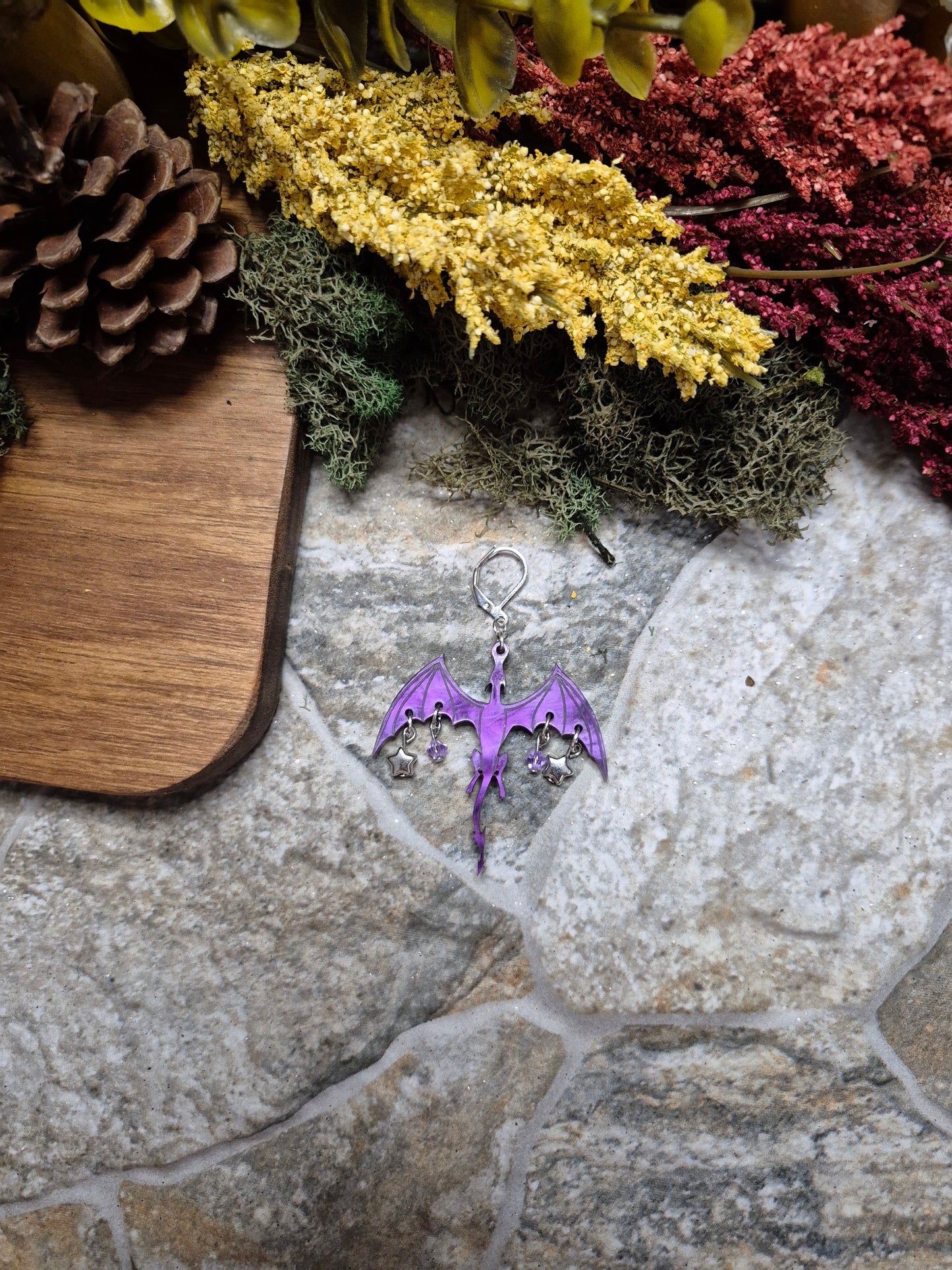 purple dragon dangle on a stone background surrounded by foliage.