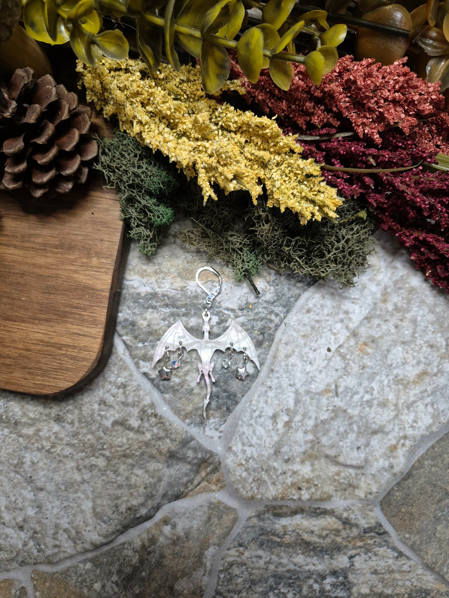 white dragon dangle on a stone background surrounded by foliage.