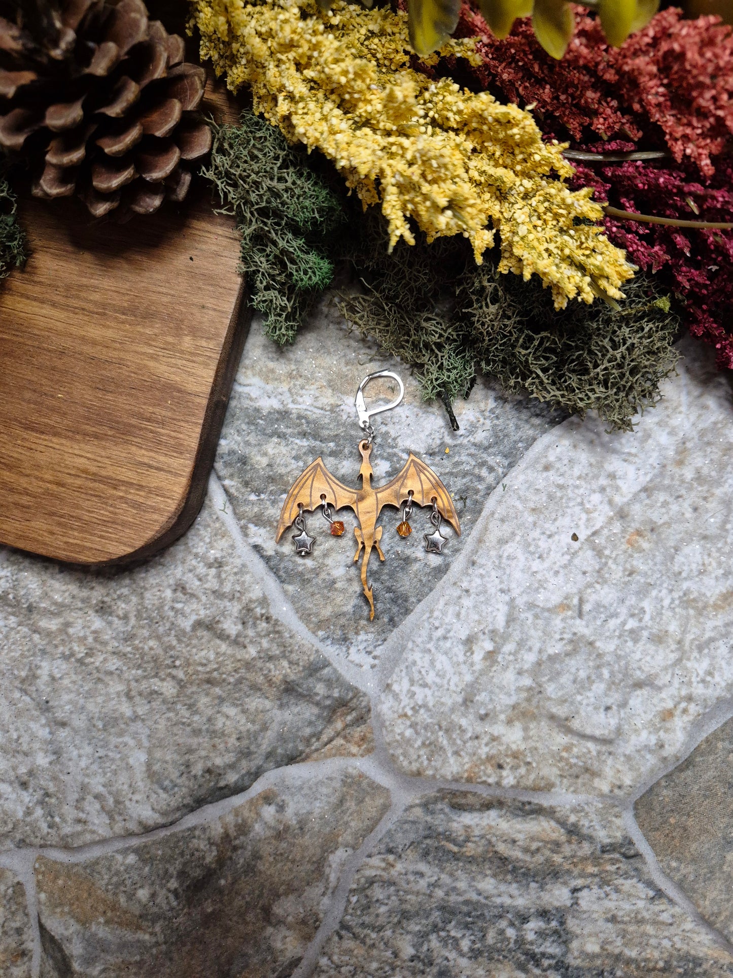 bronze dragon dangle on a stone background surrounded by foliage.