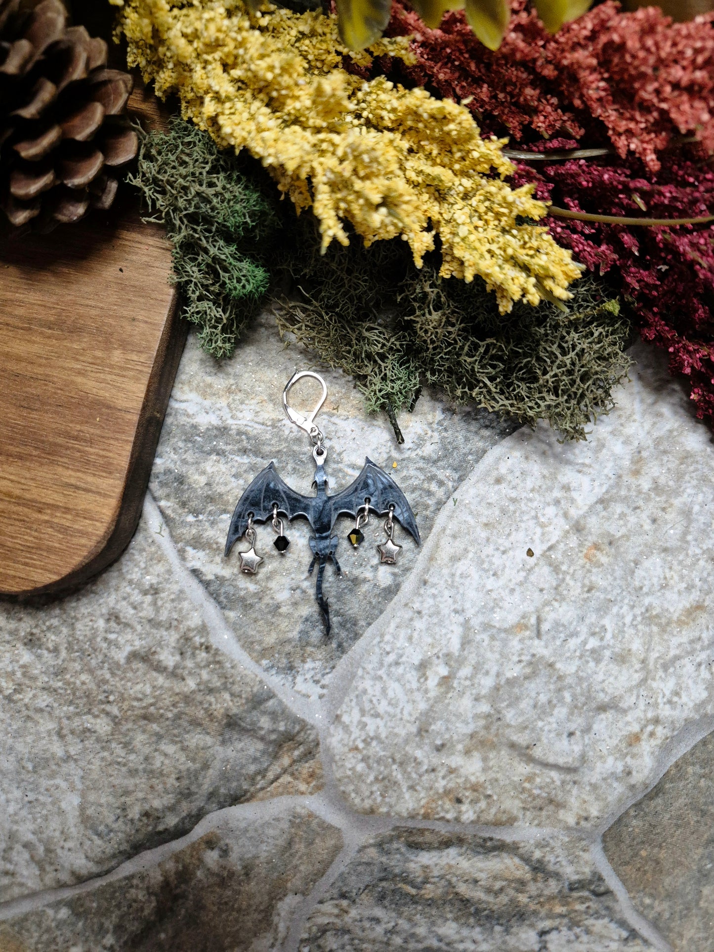 black dragon dangle on a stone background surrounded by foliage.