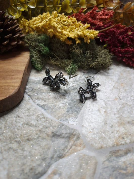 balloon dog earrings on their side and standing on a stone background surrounded by foliage.
