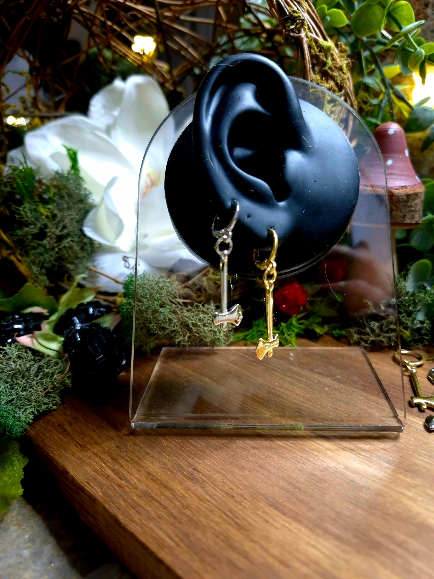 Gold and Silver Axe Earrings on a Faux ear surrounded by foliage