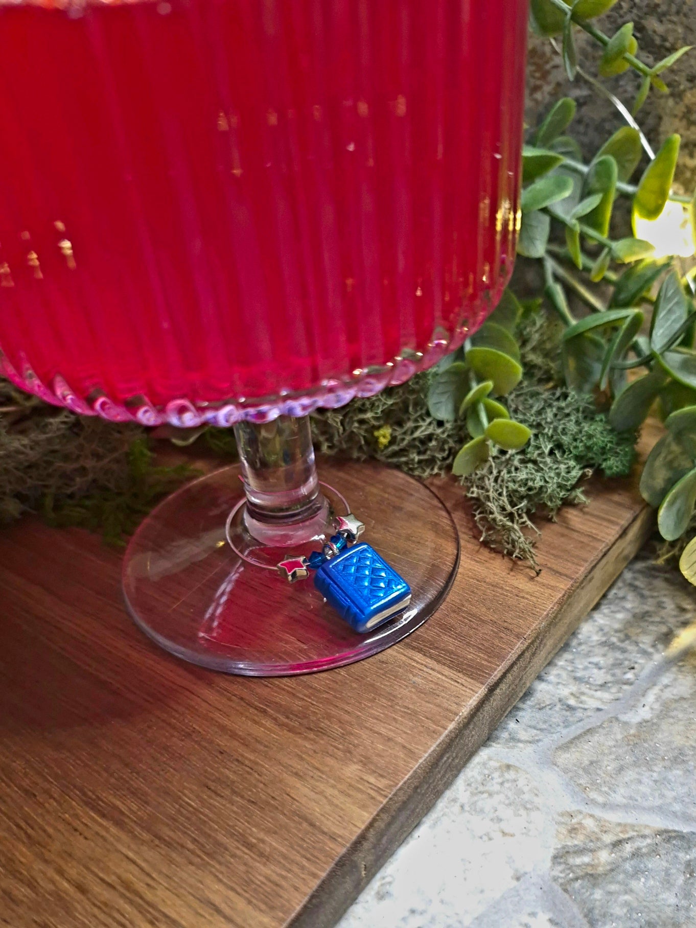 Closeup of blue book wine charm on the stem of a wine glass.