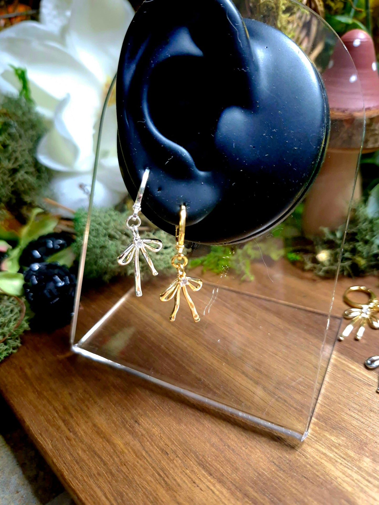Silver and Gold Bow earrings on a display ear