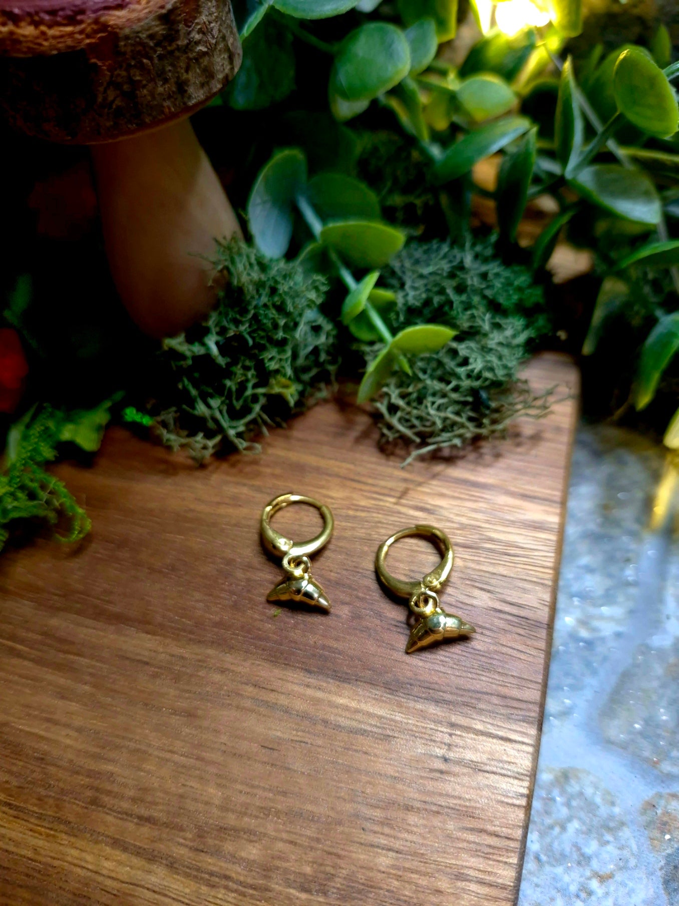 gold croissant charm earrings on wood and stone background