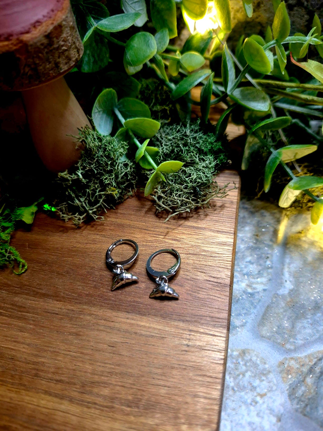 silver croissant charm earrings on wood and stone background