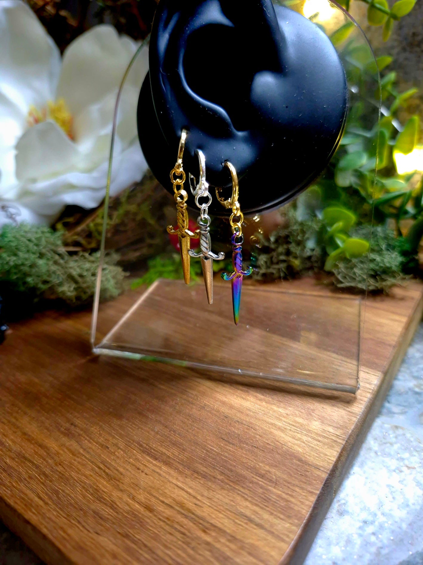 3 colors of dagger earrings on a display ear