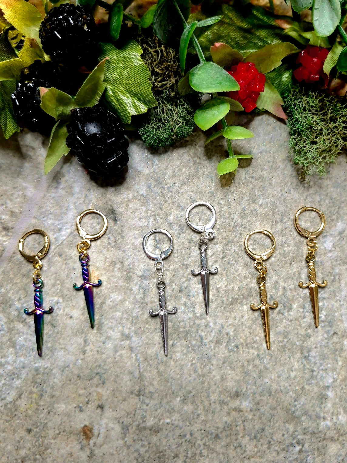 3 colors of dagger earrings on a stone background.