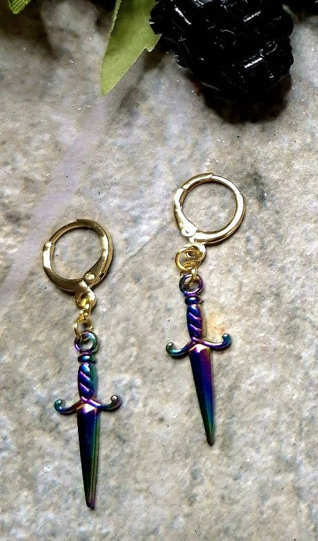 rainbow dagger earrings on a stone background.