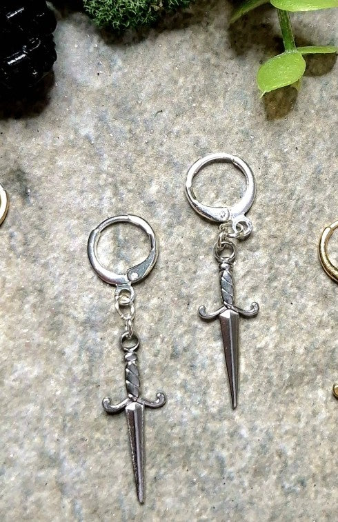 silver dagger earrings on a stone background.