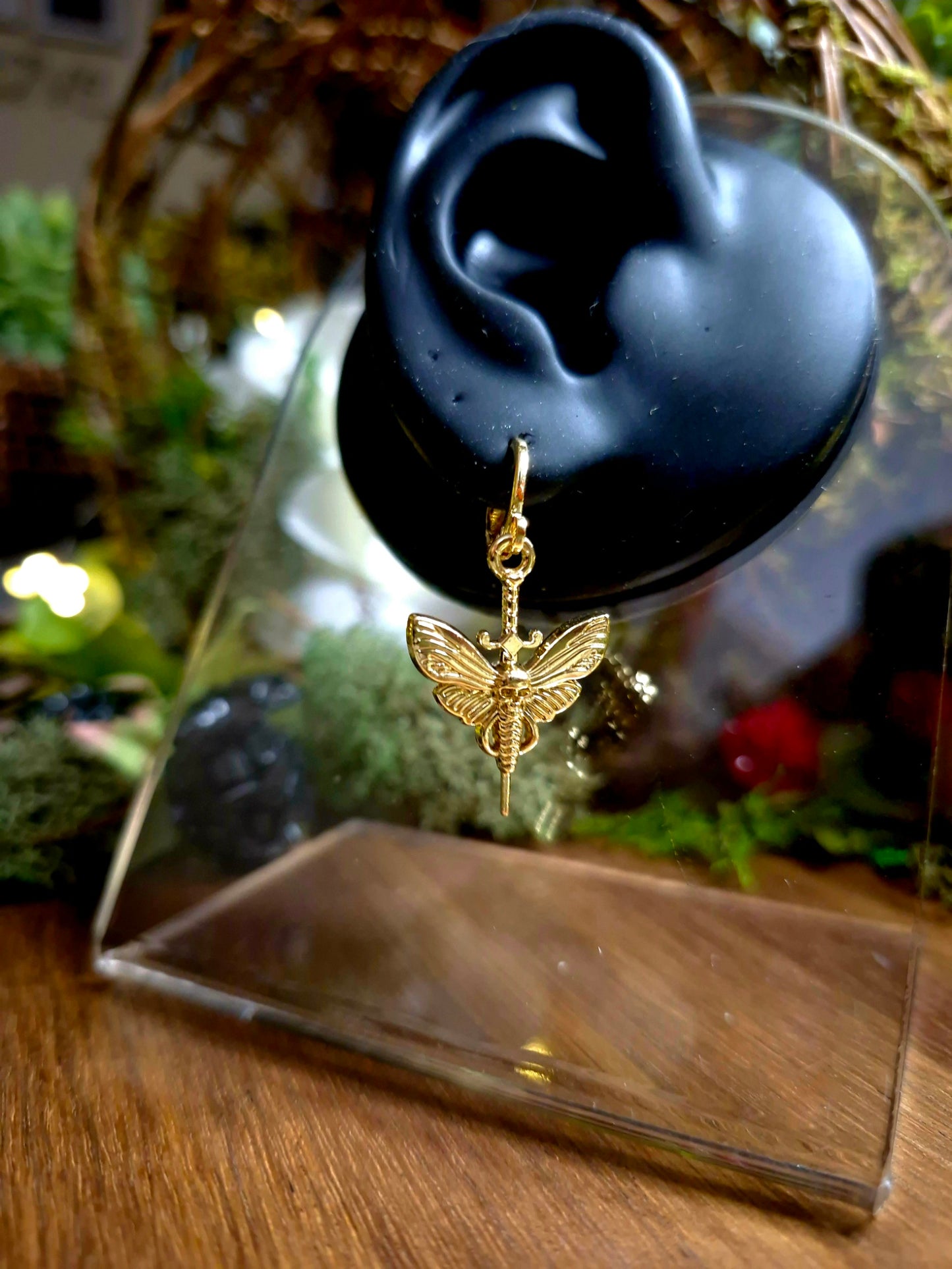 deaths head moth earrings on a display ear