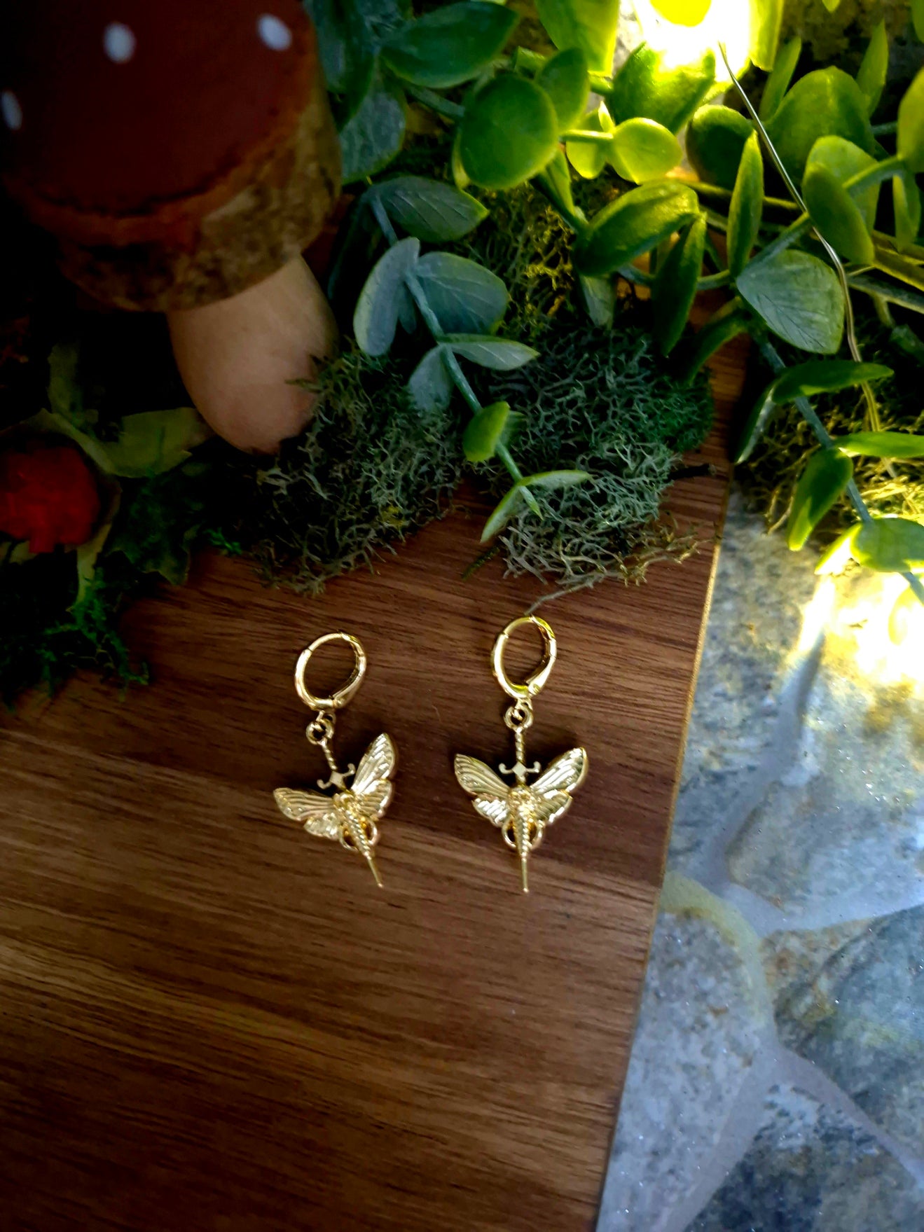 deaths head moth earrings on a wood and stone background