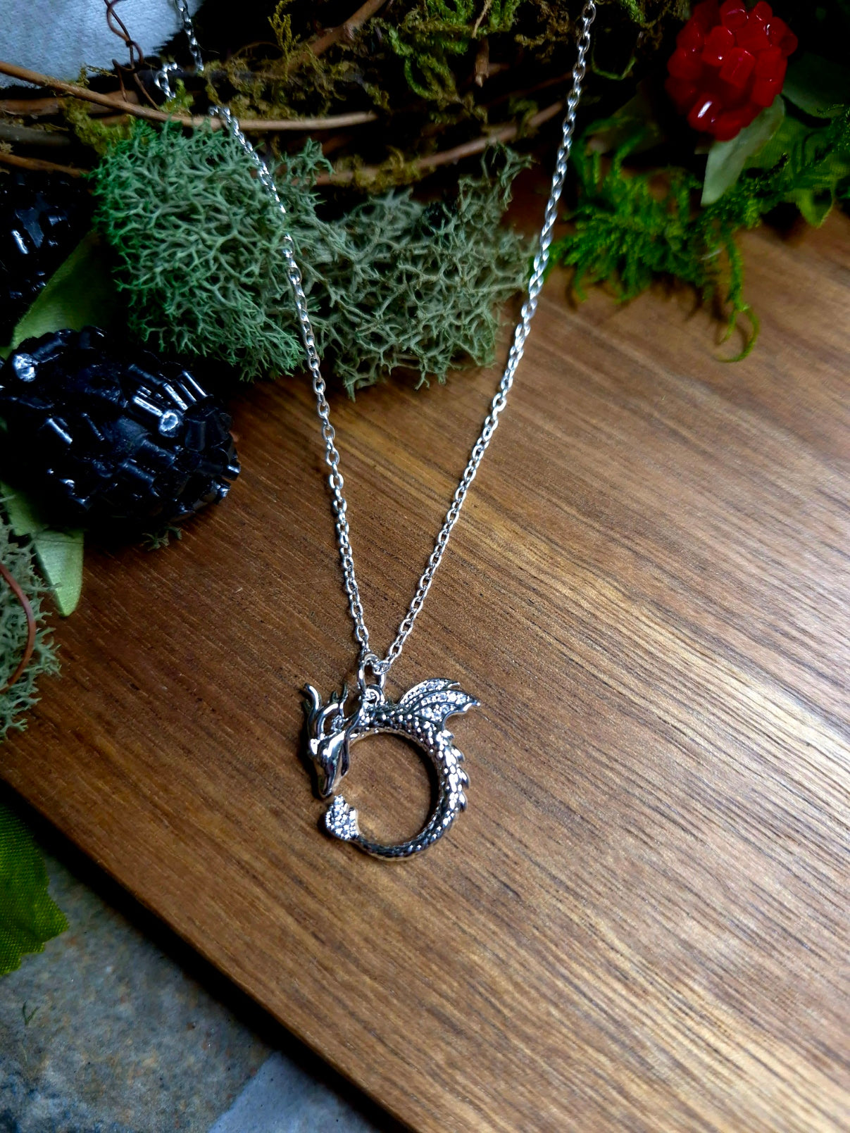 Silver Dragon Necklace on a wood and stone background.