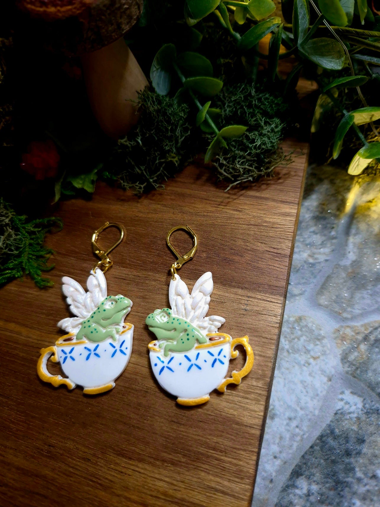 fairy frog earring on a wood and stone background