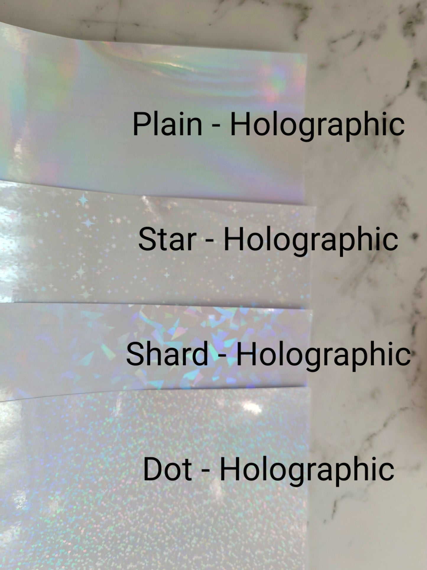 close up of plain, star, shard, and dot holographic laminate on marble background