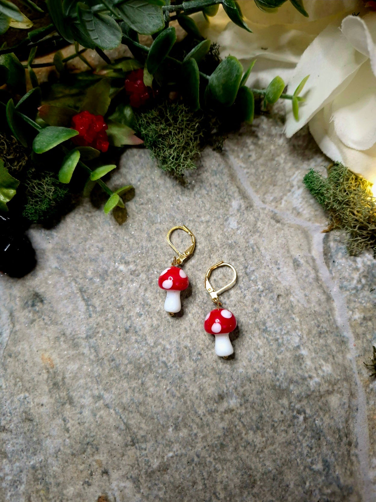 Gold Toadstool Charm Earrings on a stone background