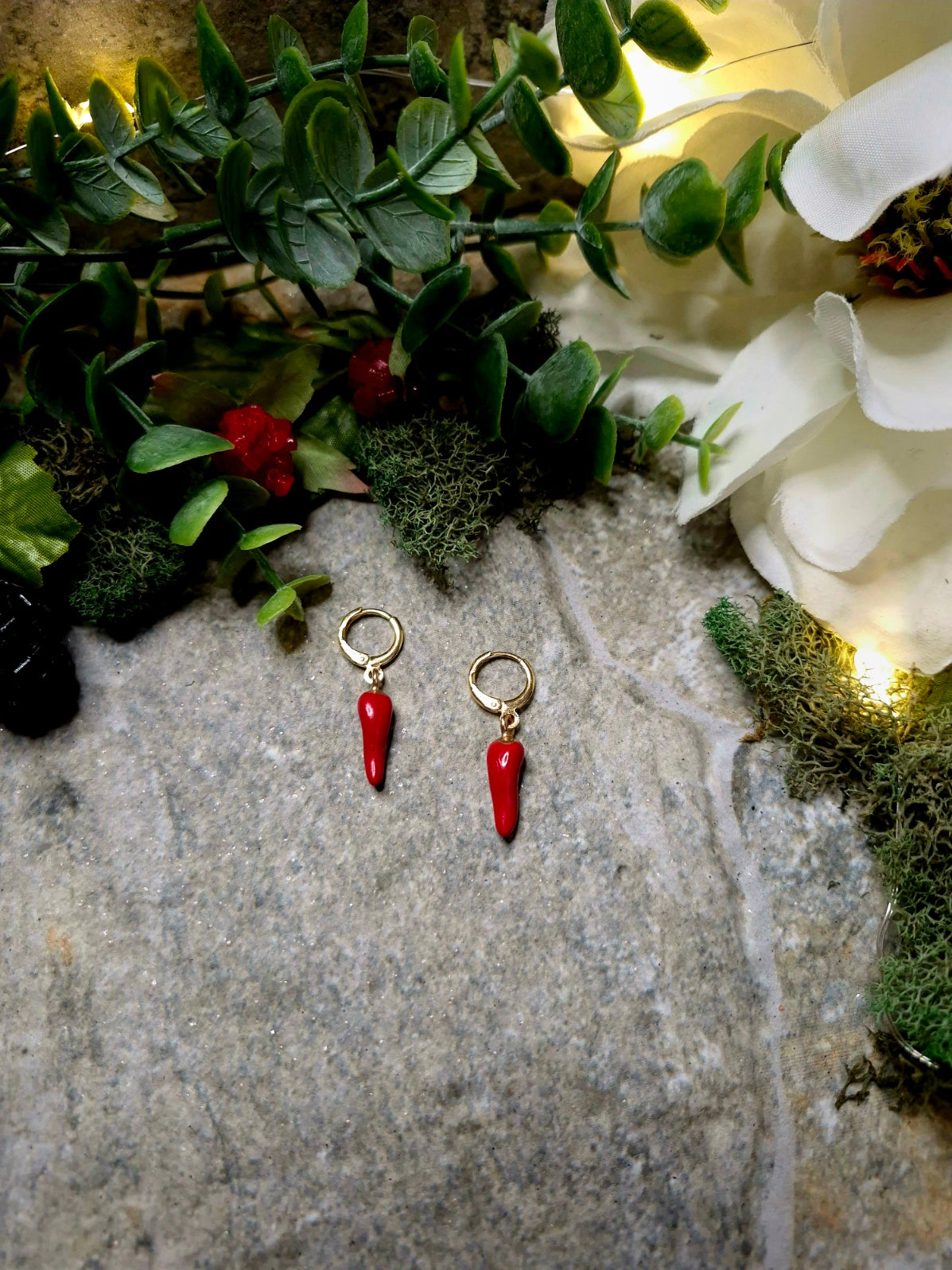 1 spice earring on a stone background surrounded by foliage