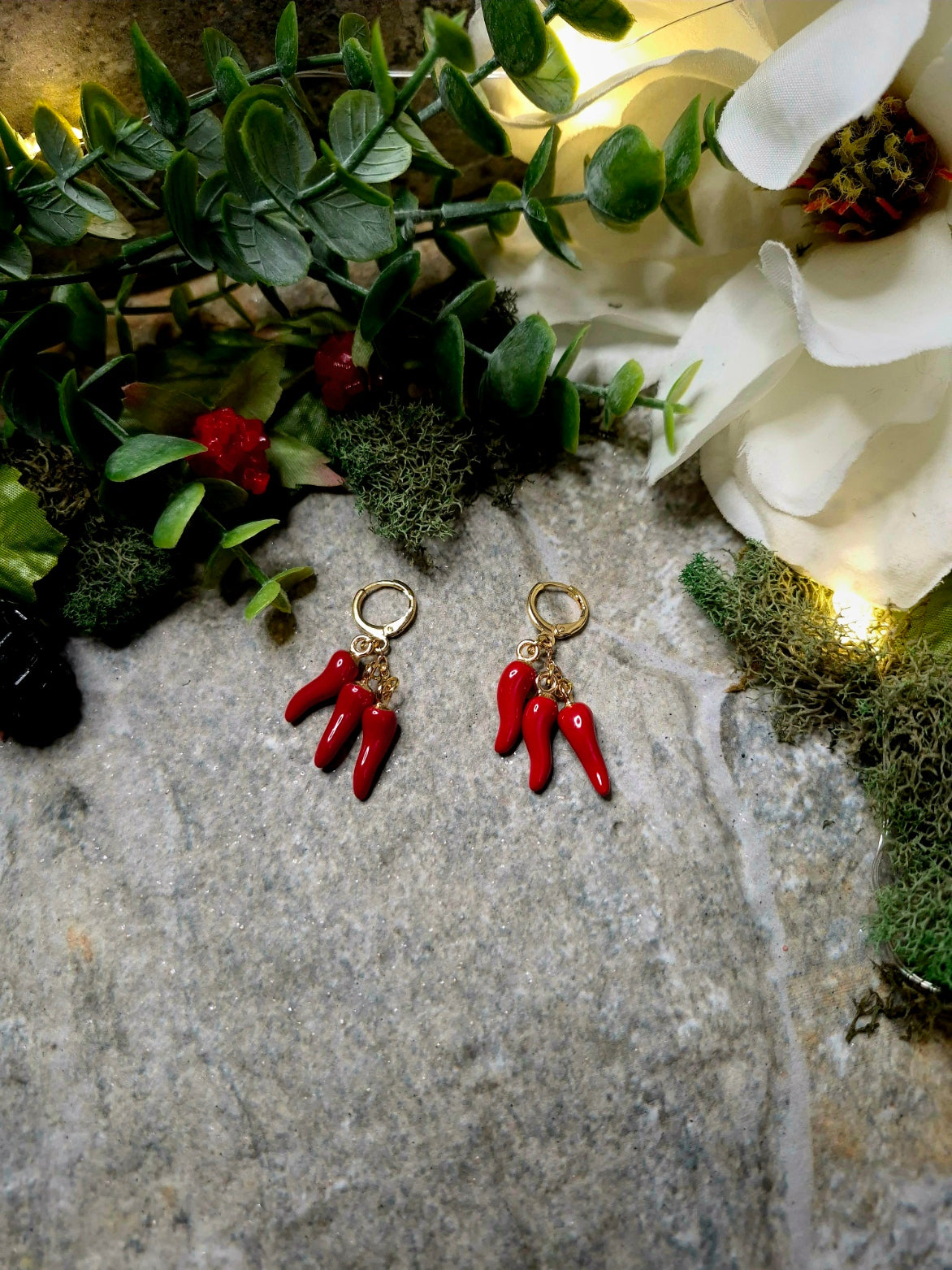 3 spice earring on a stone background surrounded by foliage