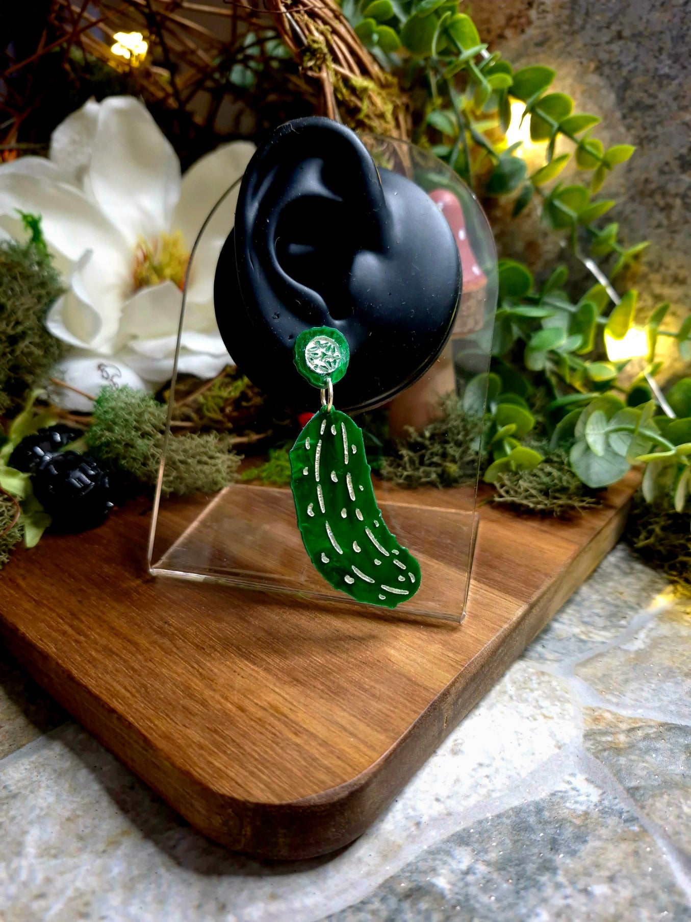 Green pickle earring on a display ear.