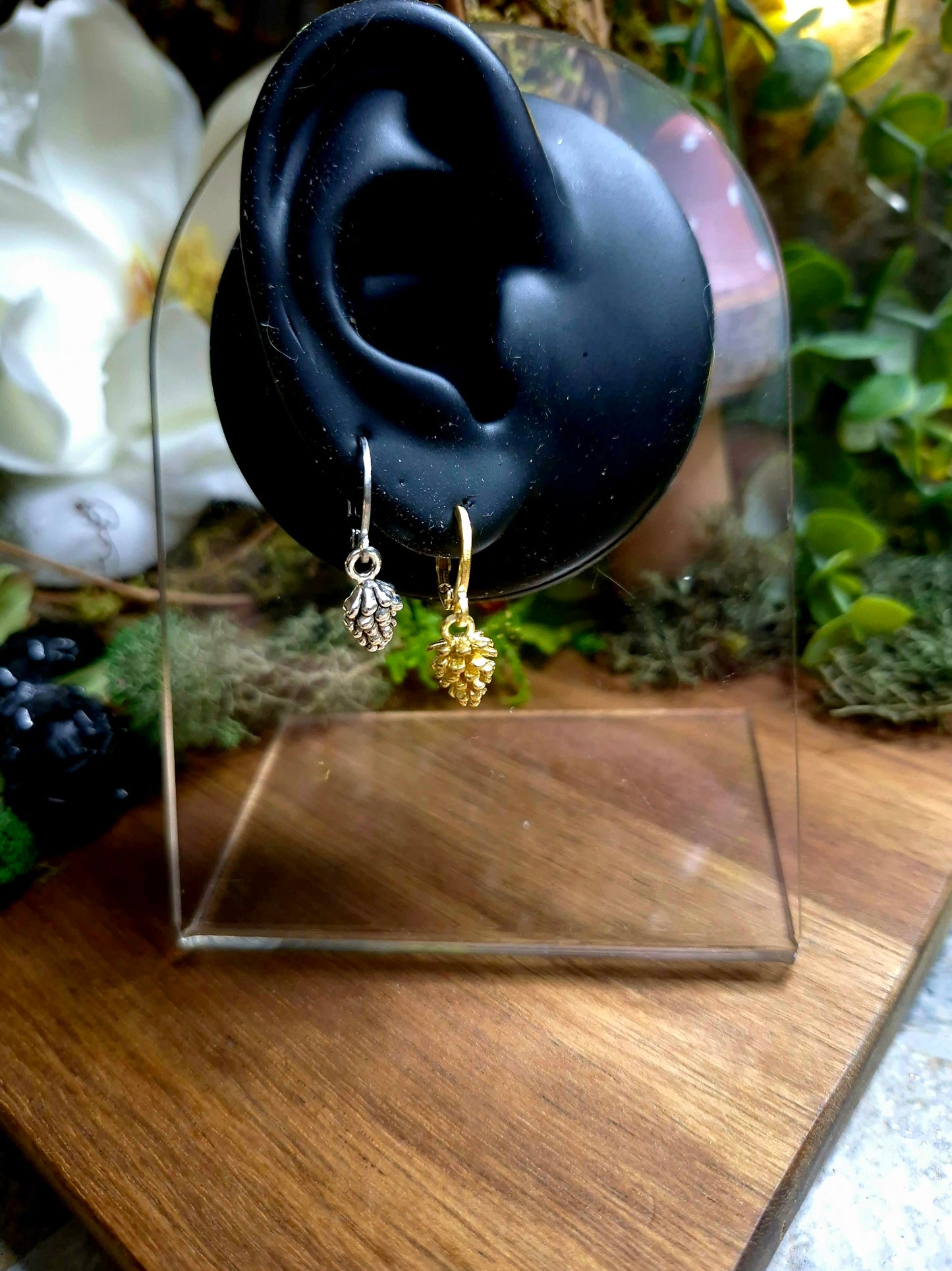 silver and gold pinecone earrings on a display ear