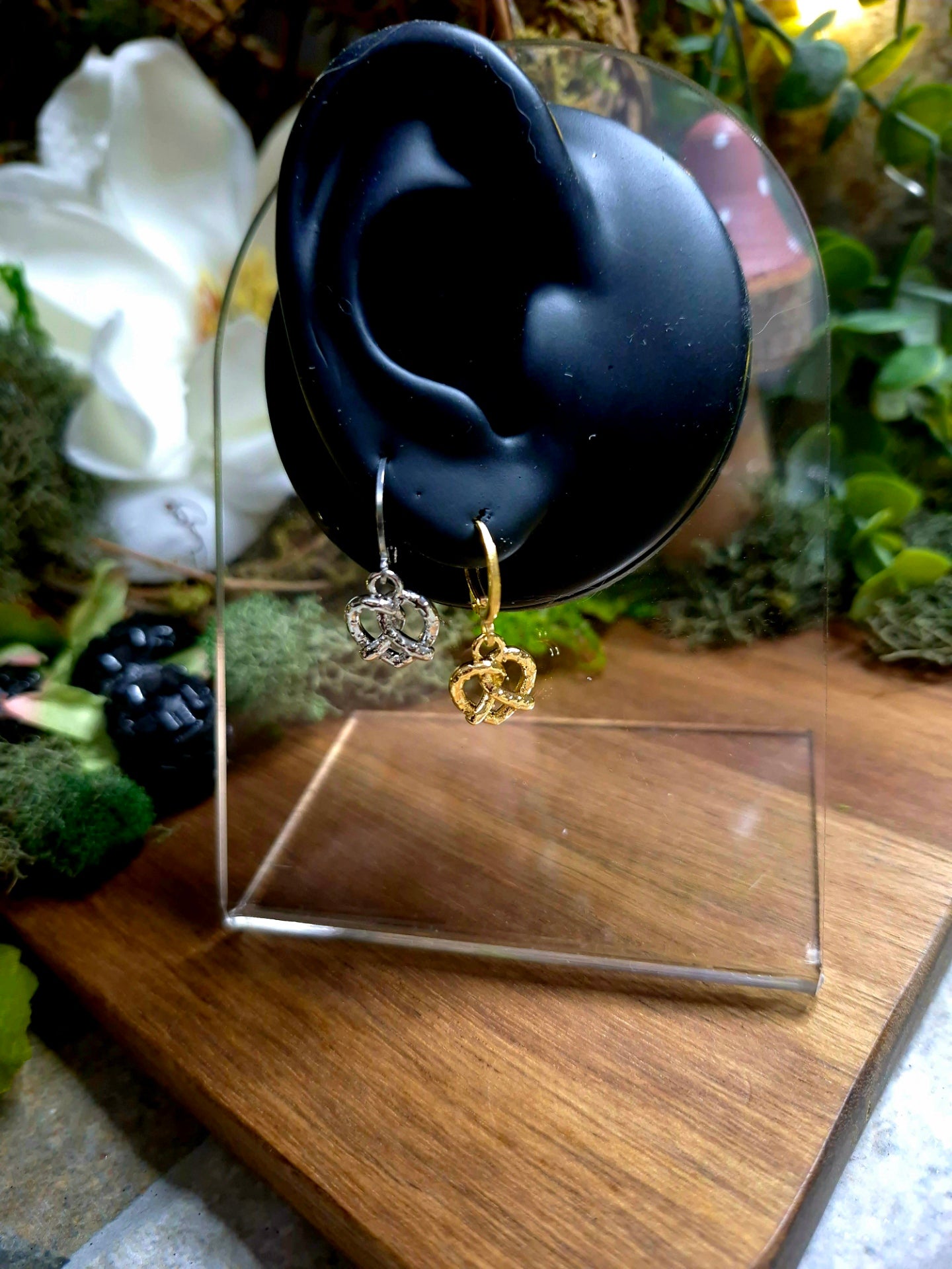 silver and gold pretzel earrings on a display ear