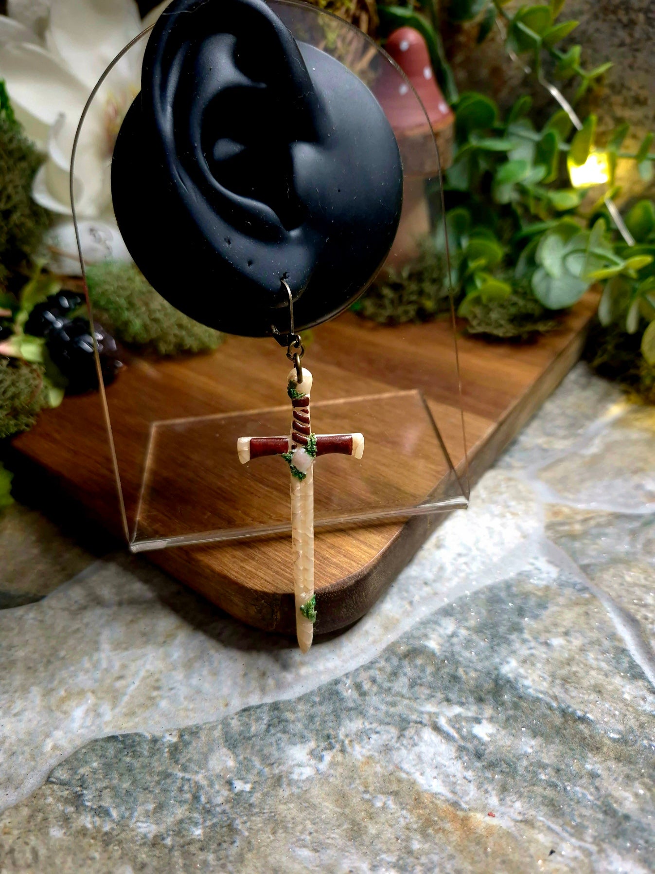 Marble and Moss Sword Earrings on display ear