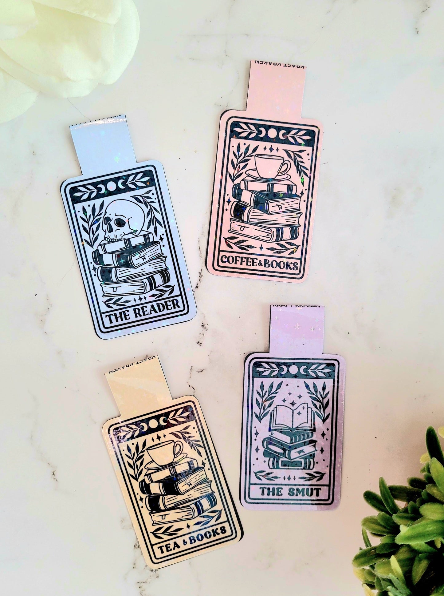 Reader, Coffee & books, Smut, Tea & books Tarot bookmarks on a marble background surrounded by foliage.