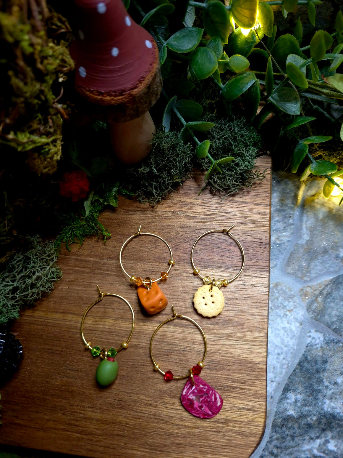 Charcuterie themed wine charms on a wood and stone background surrounded by foliage