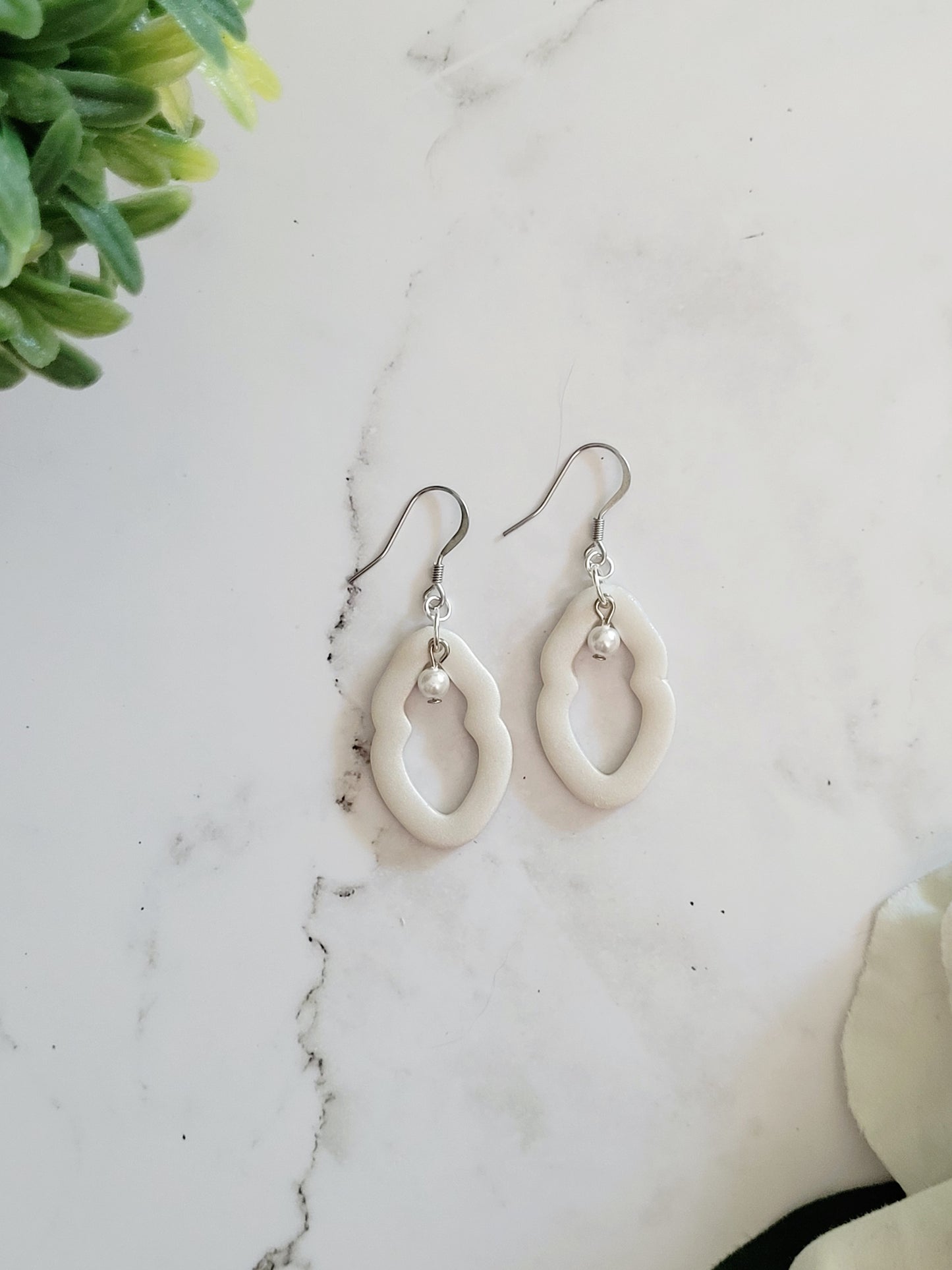 Closeup of small pearl Vulva shaped earrings with pearl bead