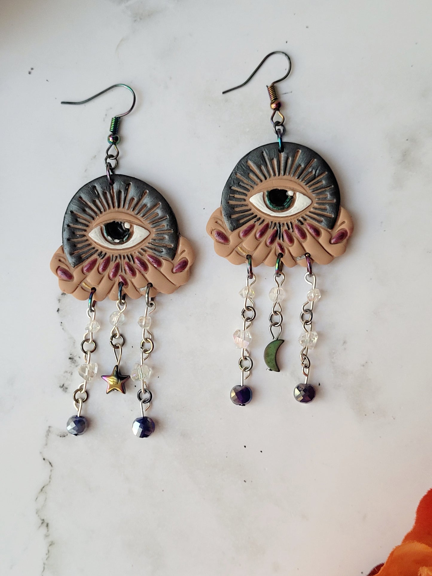close up of All seeing eye earrings in medium skin tones