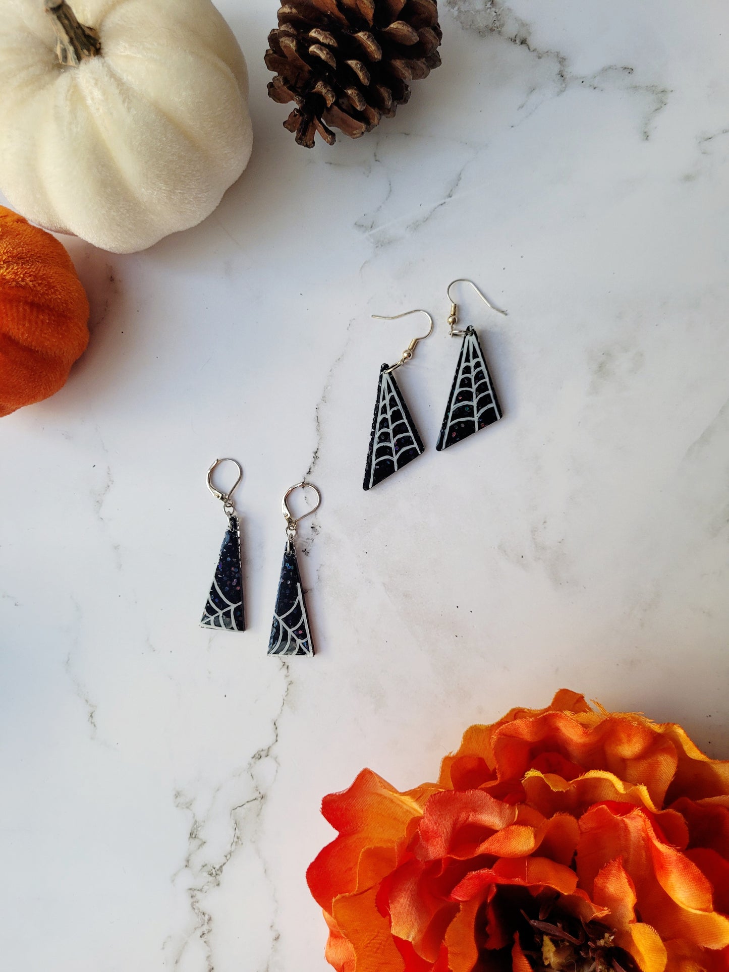 2 pairs of black glitter earrings with white spider webs