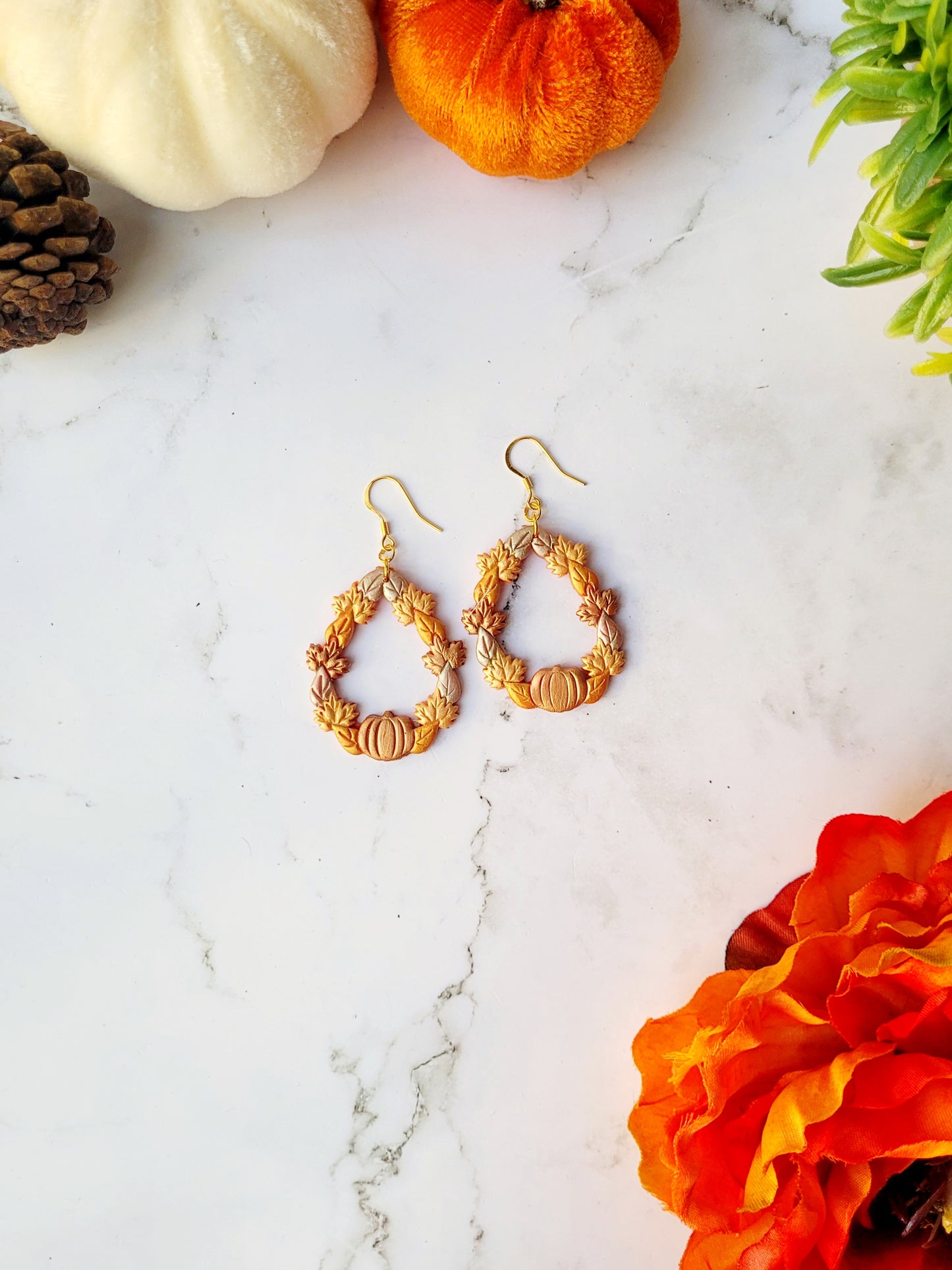 fall harvest themed teardrop earrings on a marble background
