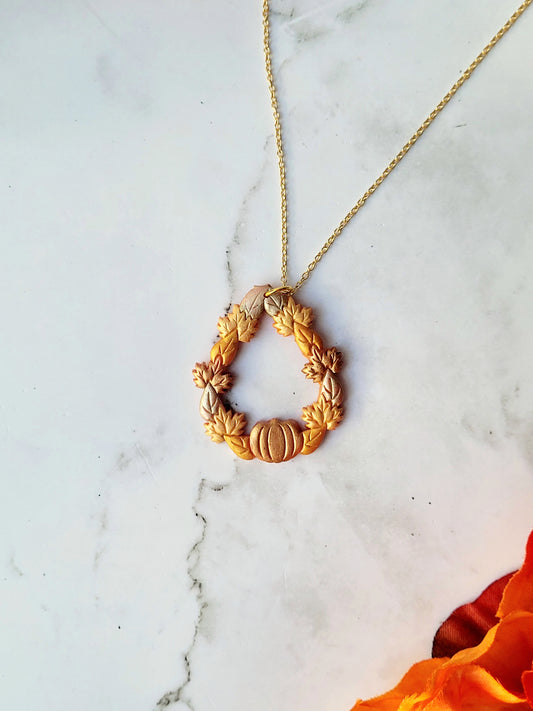 close up of fall harvest themed teardrop necklace on a marble background