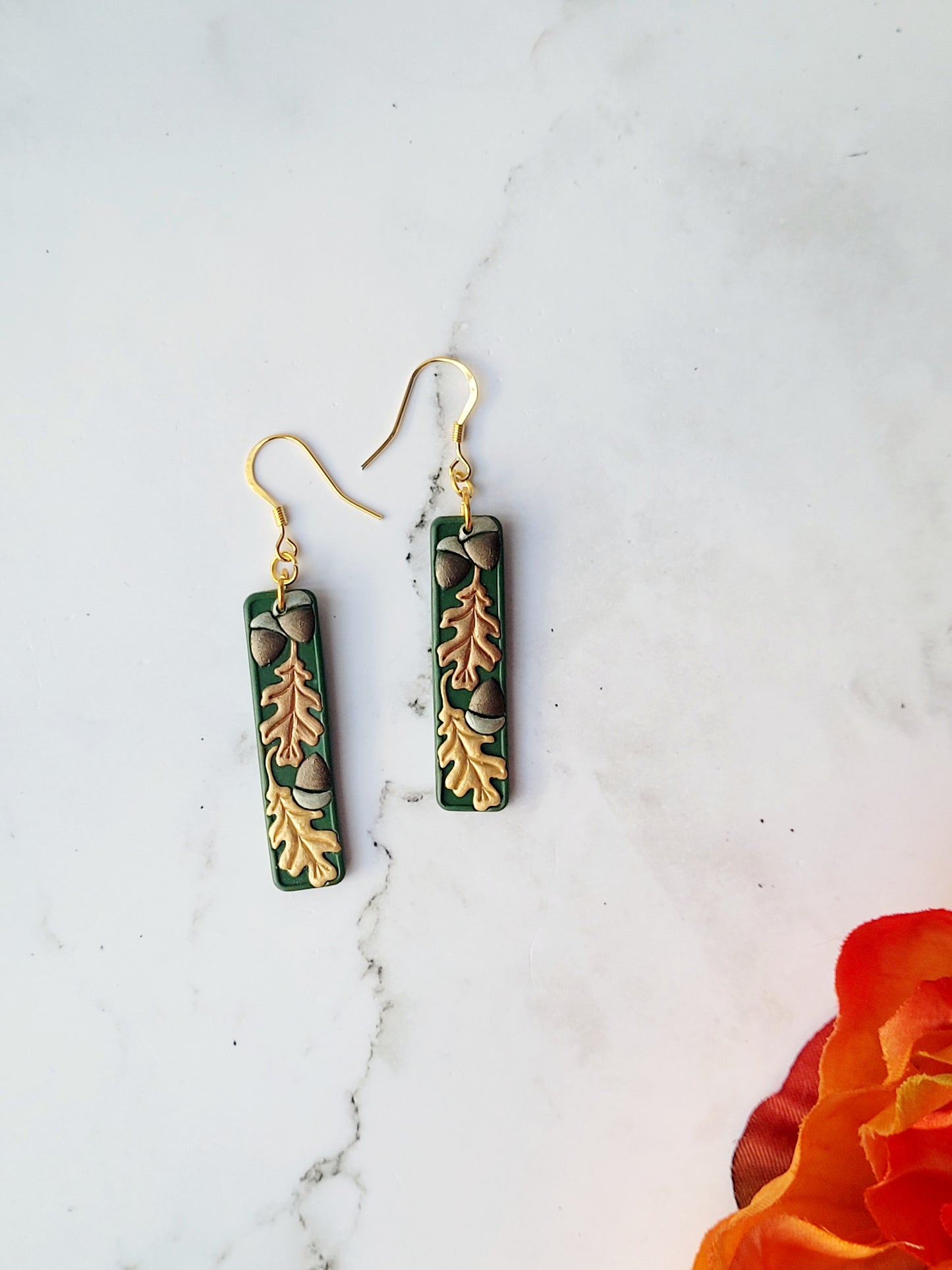 close up of the Green bar shaped earrings with metallic acorns and oak leaves.
