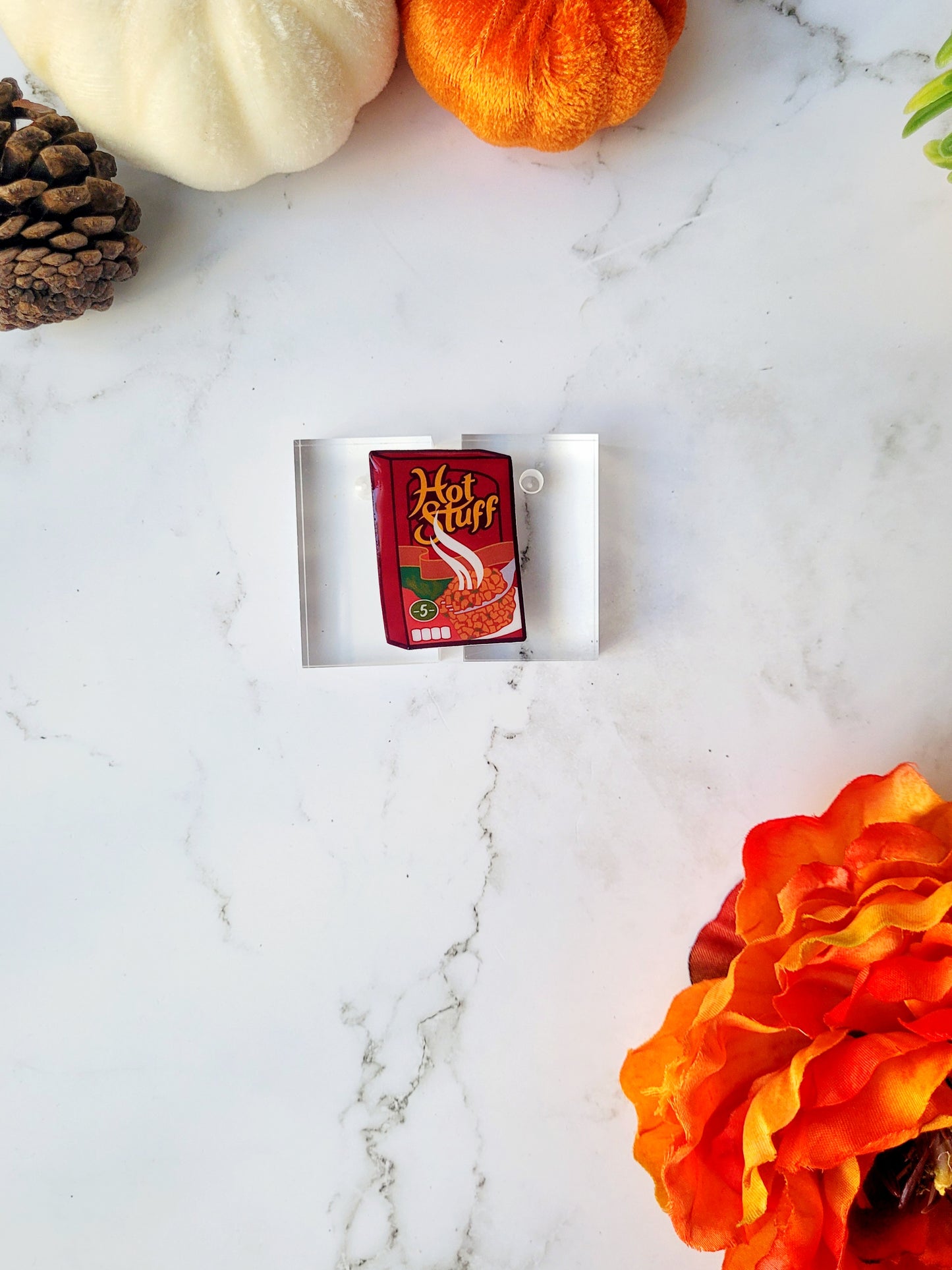 close up of stuffing box pins on a marble background with fall foliage.
