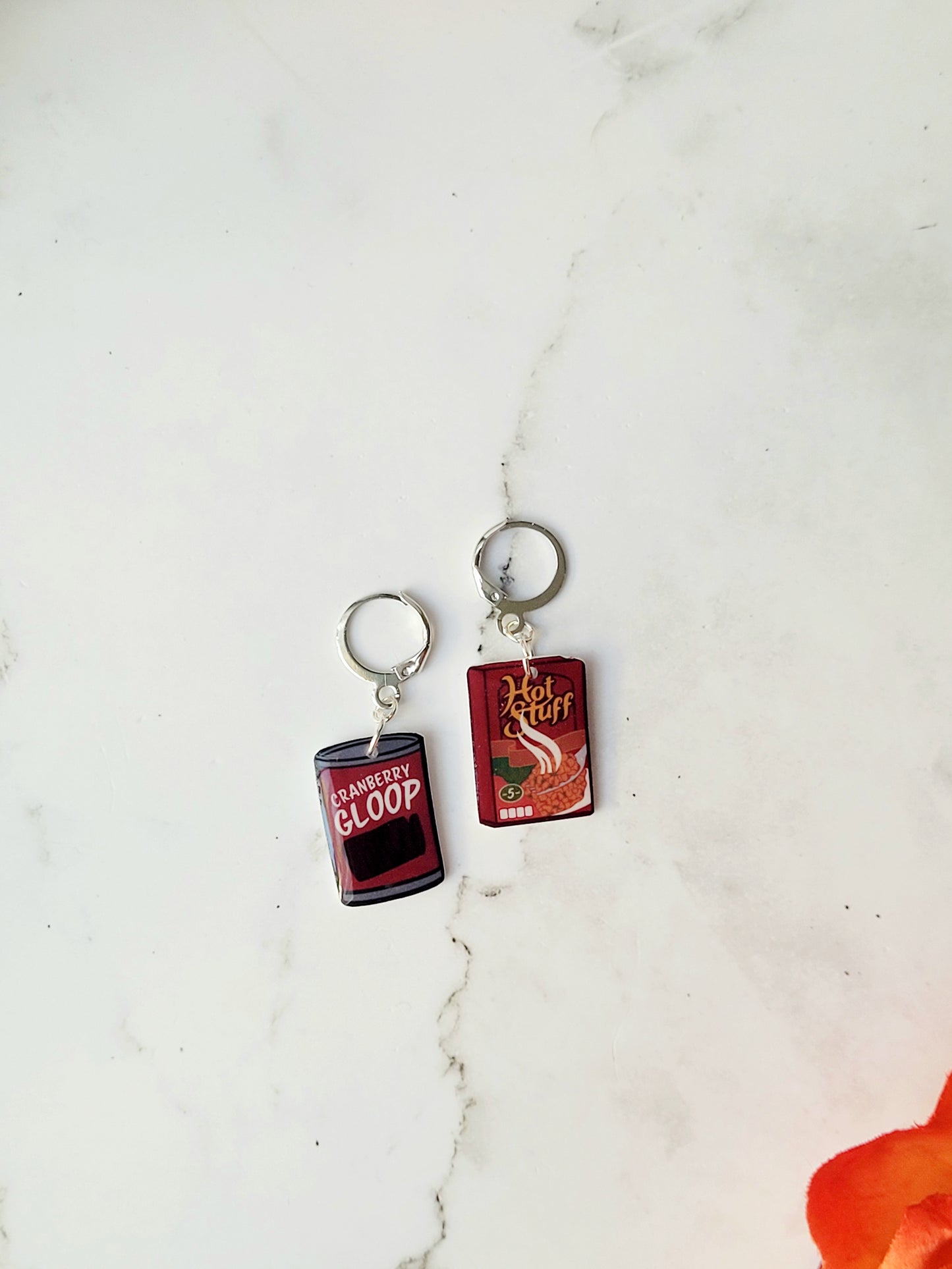 close up of mis-match earrings on a marble background with fall foliage.