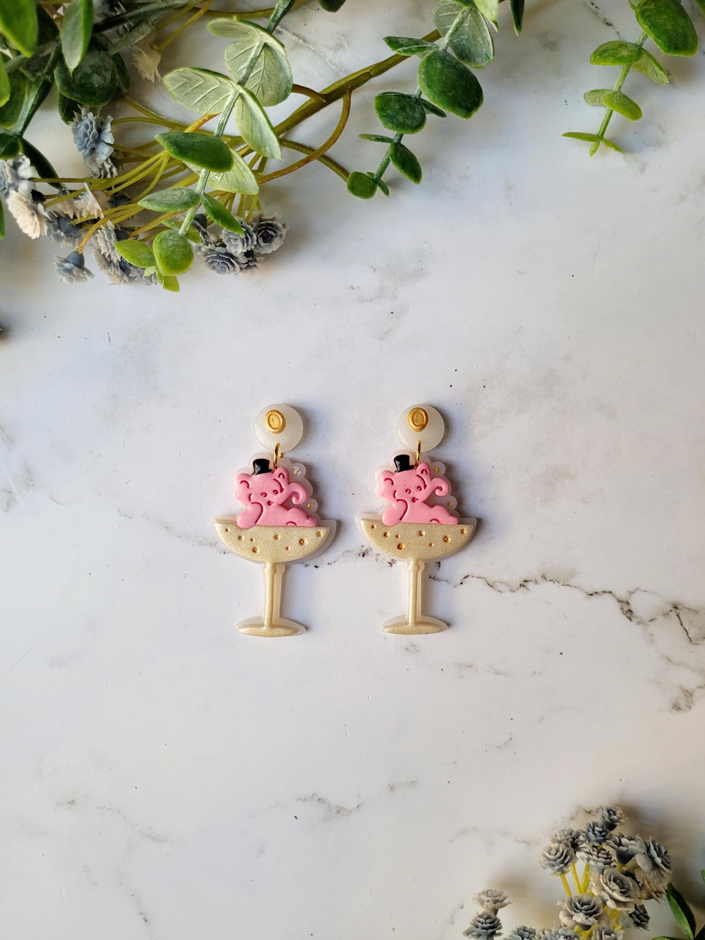 Pink Elephant in a champagne coupe earrings on a marble background .