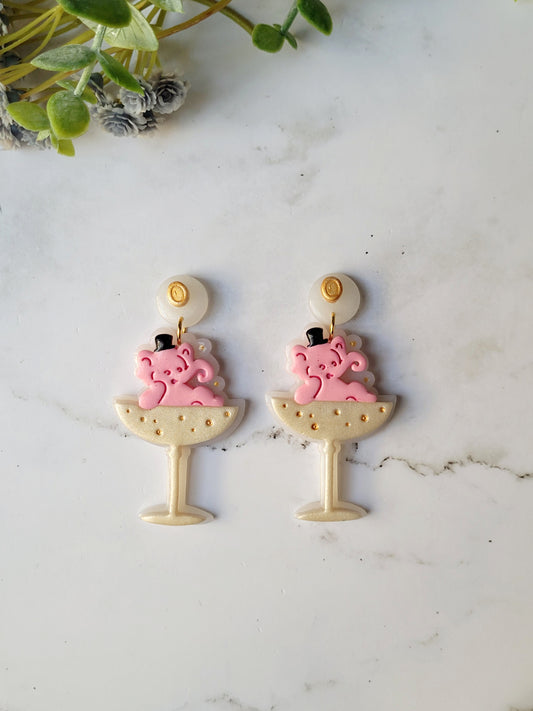close up of Pink Elephant in a champagne coupe earrings on a marble background .